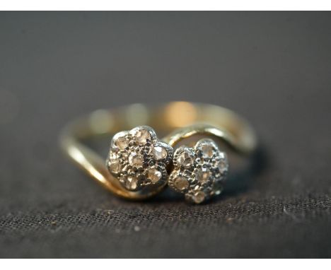 An Edwardian yellow metal (tests higher than 9ct) and rose cut diamond floral cross over ring, each of the flowers set with a