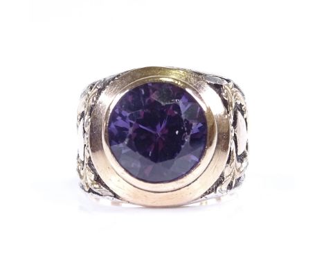 A large early 20th century unmarked silver and gold synthetic sapphire ring, raised foliate and shield shoulders and shank, s