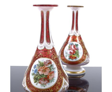 A pair of Bohemian ruby and milk overlay glass narrow-necked vases, with hand painted floral panels and gilded decoration, he