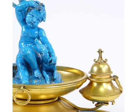 An ornate 19th century French gilt-metal desk stand, surmounted by a blue glazed ceramic cherub and dog, height 28cm, length 