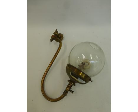 A brass gas lamp with glass shade.