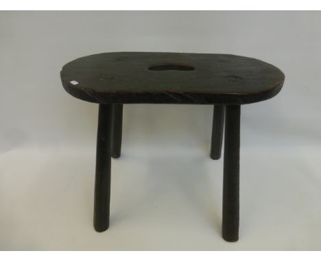 An early 19th Century primitive green painted elm stool with cut out handle.