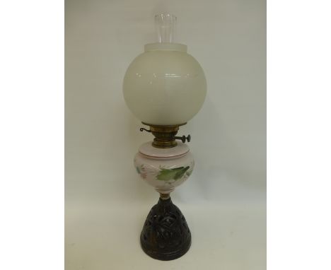 A Victorian oil lamp with painted opaline glass reservoir above a pierced metal base, with rounded etched glass shade.