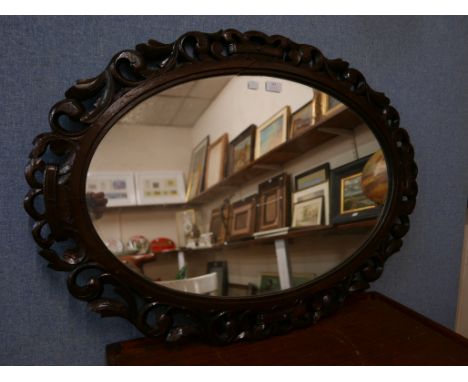 An Edward VII carved oak oval framed mirror 