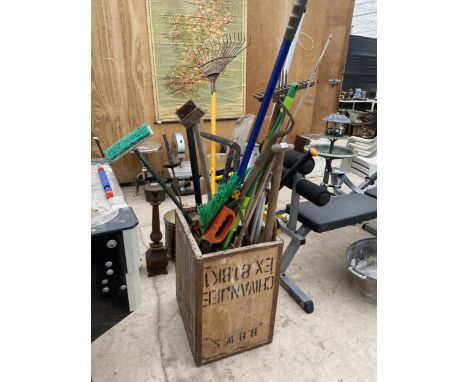 A VINTAGE TEA CHEST CONTAINING AN ASSORTMENT OF GARDEN TOOLS TO INCLUDE RAKES, SAWS AND SHEARS ETC 