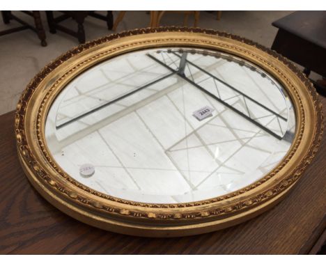 AN OVAL GILT FRAMED WALL MIRROR, 22" X 18" 