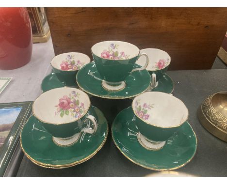 FIVE ADDERLEY CHINA CUPS AND SIX SAUCERS IN A DARK GREEN WITH A FLORAL PATTERN 