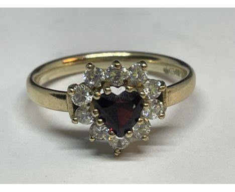 A 9 CARAT GOLD RING WITH A CENTRE HEART SHAPED RED STONE SURROUNDED BY CUBIC ZIRCONIAS SIZE M 