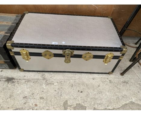 A LARGE METAL BOUND TRAVEL TRUNK WITH BRASS EFFECT HINGES AND FASTENS 