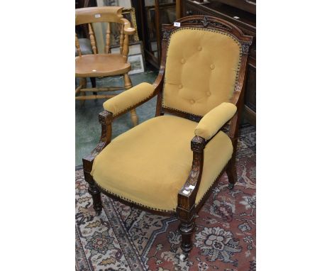 A Victorian mahogany lady's open arm chair, carved top rail, button back, padded arms, stuffed overseat, turned forelegs, cer