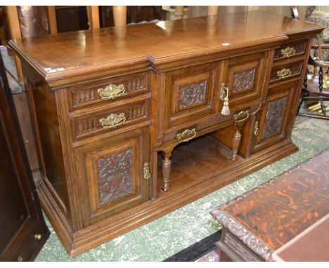 A Victorian oak breakfront sideboard, moulded oversailing top, two carved fielded panel door cupboard over long drawer and re