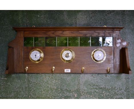 An oak wall mounted tile back coat rack with clock, barometer, temperature and humidity gauge. 