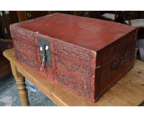 A Chinese red lacquered rectangular travelling trunk or document box, hinged cover, brass hasp, the front decorated in relief