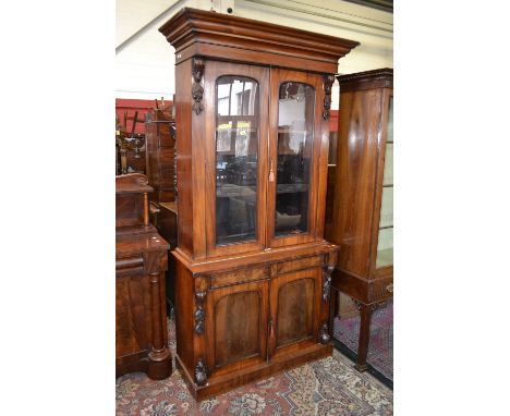 A Victorian mahogany library bookcase, stepped cornice, two arched glazed doors enclosing shelving to top, two short drawers 