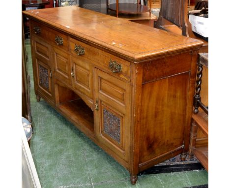 A late Victorian sideboard, oversailing top, two long drawers, pierced brass batwing escutcheons, swing handles, two fielded 