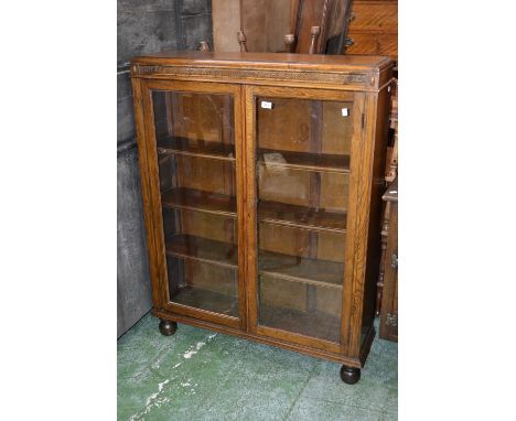 An oak bookcase with two glazed panel doors