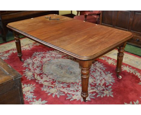 A Victorian mahogany wind out dining table with two leaf's, moulded oversailing top above a deep frieze, turned tapering legs