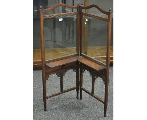 A late Victorian bi-fold firescreen, turned finials, arched glazed panels over folding shelves, shaped supports.