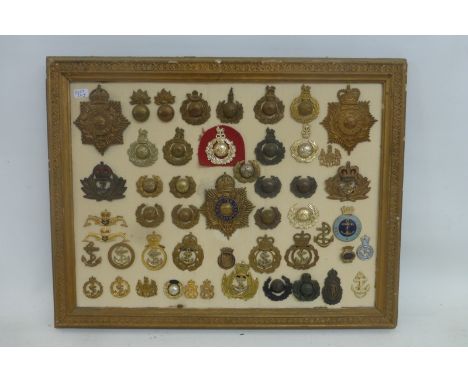 A framed display of 52 mainly Royal Marines cap, helmet and lapel badges. All appear to retain their fixings to the reverse.