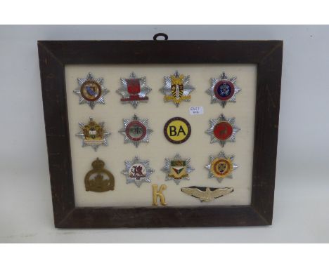 A framed display of 14 chrome and enamel fire brigade cap badges with some military badges, average size of fire brigade badg