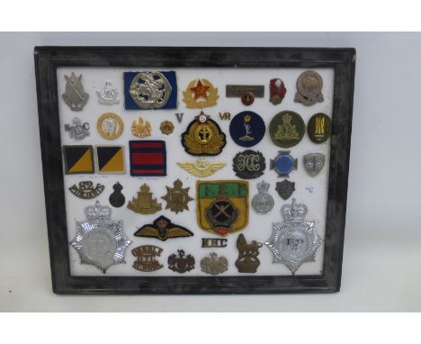 A framed display of 39 police and military badges. The Gloucestershire Constabulary helmet badge is approximately 4 1/2 x 3 3