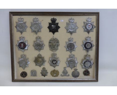 A framed display of 20 police helmet badges and two military badges, average size of the helmet plates approximately  4 3/4 x