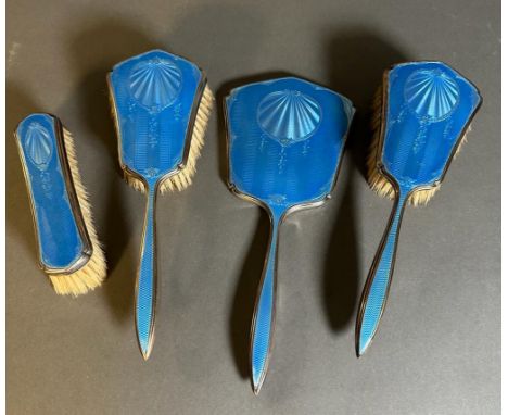 A blue enamel and silver, hallmarked for Birmingham dressing table set comprising three brushes and a handheld mirror.