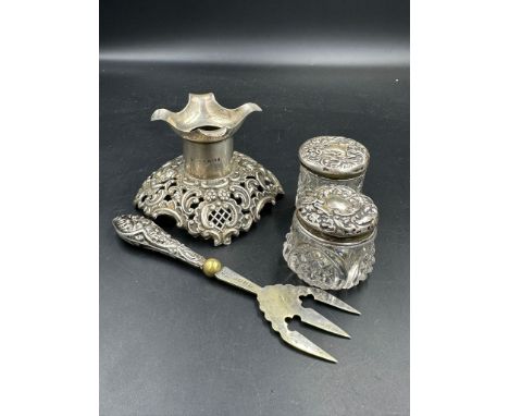 A selection of hallmarked items to include a stand, two silver topped jars and silver handled pickle fork.