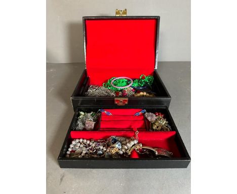 A Black jewellery box with a selection of costume jewellery including a silver enamel bracelet.