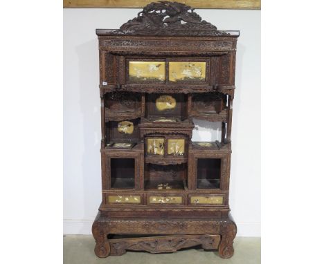 A late 19th century early 20th century profusely carved hardwood Oriental cabinet on stand - with gilt lacquered ivory inset 