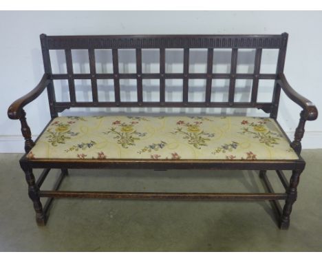 An oak carved settle with open arms and upholstered seat - Width 1.4 m