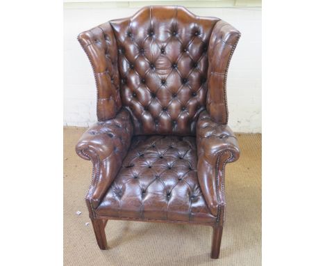 A good buttoned brown leather wing back armchair in the Georgian style- Height 1.2 m x Width 84 cm  x Depth 82 cm 