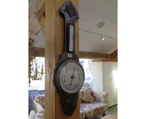 An oak cased banjo barometer - carved leaf decoration above and below silvered thermometer with farenheit and centigrade scal