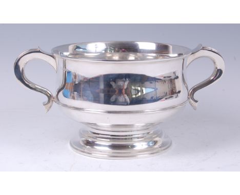 An Art Deco silver twin handled pedestal trophy cup, by Garrard & Co, of circular squat form, having rat-tail S scroll handle