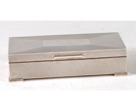 A late Art Deco engine turned silver table cigarette box, the hinged cover with vacant rectangular cartouche enclosing a ceda