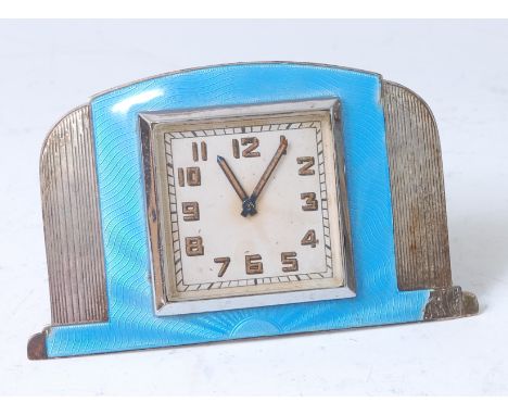 An Art Deco sterling silver and blue guilloche enamel decorated bedside clock, having a square dial and Smiths winding mechan