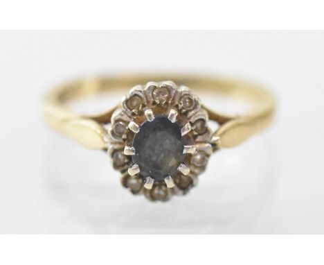 A 9ct yellow gold sapphire and diamond set ring, the central sapphire surrounded by multiple small diamonds, size K, approx 2