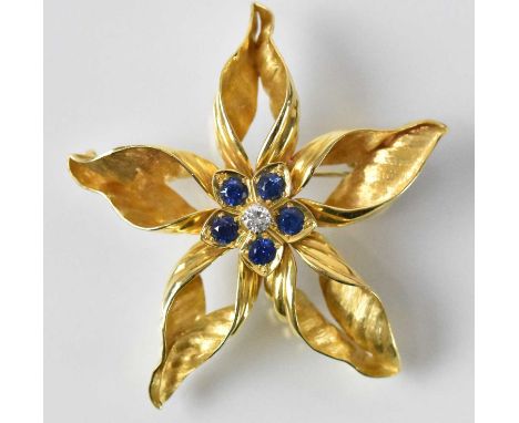 An 18ct yellow gold diamond and sapphire set flower brooch, the central stone approx 0.2ct, surrounded by five sapphires, sap