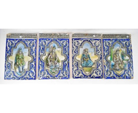A set of four 18th/19th century large Persian tiles with raised detail and each centred with a figure within shaped panel and