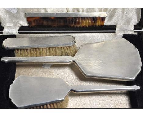 A cased four piece silver backed dressing table set comprising hand mirror, clothes brush, hair brush and comb, Birmingham 19