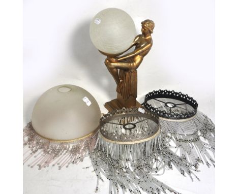 An Art Deco style gilded figure of a lady holding a crackle glass ball lamp shade and three Art Deco style beaded lamp shades