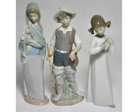 A Lladro figure of a fisherman in waders, height 23cm, a Lladro figure of a young lady holding flowers and a further Lladro f