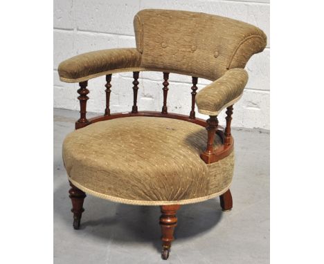 A reproduction tub chair, beige upholstered padded button back, ring turned supports to ring turned front legs on castors.