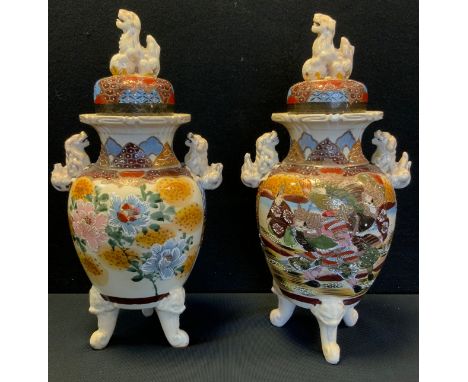 A pair of Japanese Satsuma pottery temple jars and covers, painted with traditional figural and floral panels, tripod stile f
