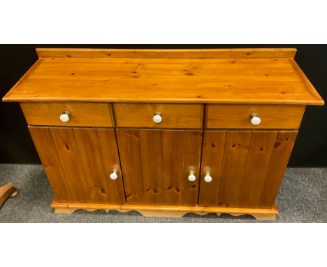 A pine sideboard, three short drawers to frieze, above three cupboard doors, white ceramic knobs, 89cm high x 131.5cm wide x 