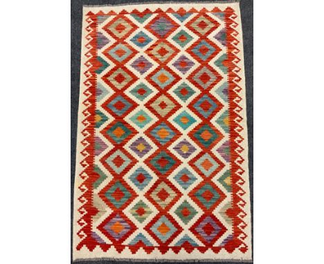 A Turkish Anatolian Kilim rug / carpet, knotted in vibrant tones of red, jade green, orange, and blue, on a pale cream ground