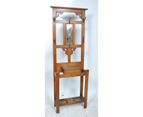 A 1920's dark oak hallstand with central glove drawer having mirror upright with coat hooks and stick stand being set to the 