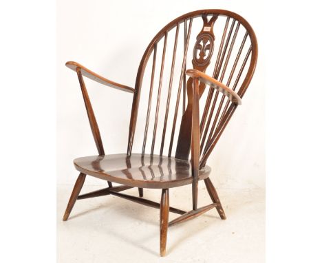 An original mid 20th century beech and elm Ercol Fleur De Lys pattern armchair having shaped elbow supports with tapering leg