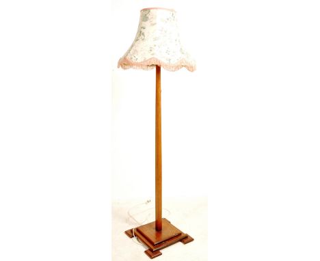 An early 20th century Art Deco oak standard lamp having a tapering column raised on a stepped base with angular feet below.&n