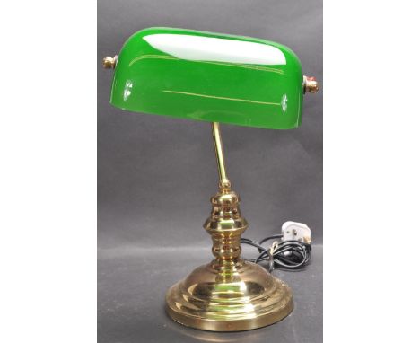 A 20th Century vintage bankers desk / table lamp light of brass construction having an adjustable green glass shade supported